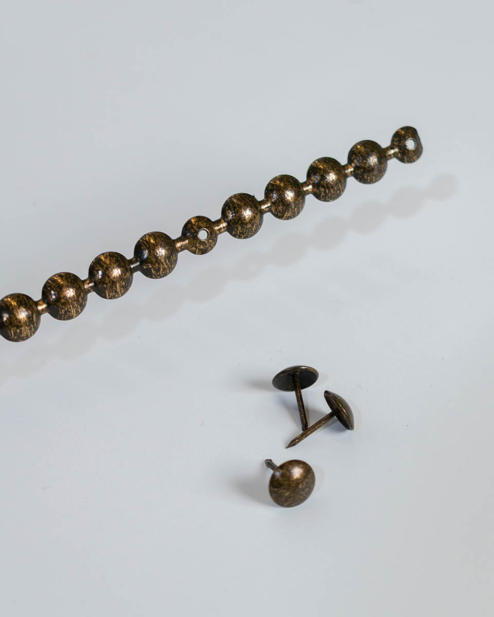 Cordón Clavo YL005, 11 mm., 100 cms., 50 unds.-Guirnalda de Clavos Tapiceros AS YL005 Aporta un acabado sofisticado y detallado a tus muebles con la Guirnalda de Clavos Tapiceros AS YL005. Diseñada para facilitar la instalación y mantener una alineación perfecta, esta guirnalda de clavos ofrece un estilo clásico y elegante en cada aplicación. Su acabado envejecido en varios tono le otorga un aire vintage y refinado, ideal para sofás, sillas, cabeceras y otros muebles tapizados. Características: ✔ Diseño en