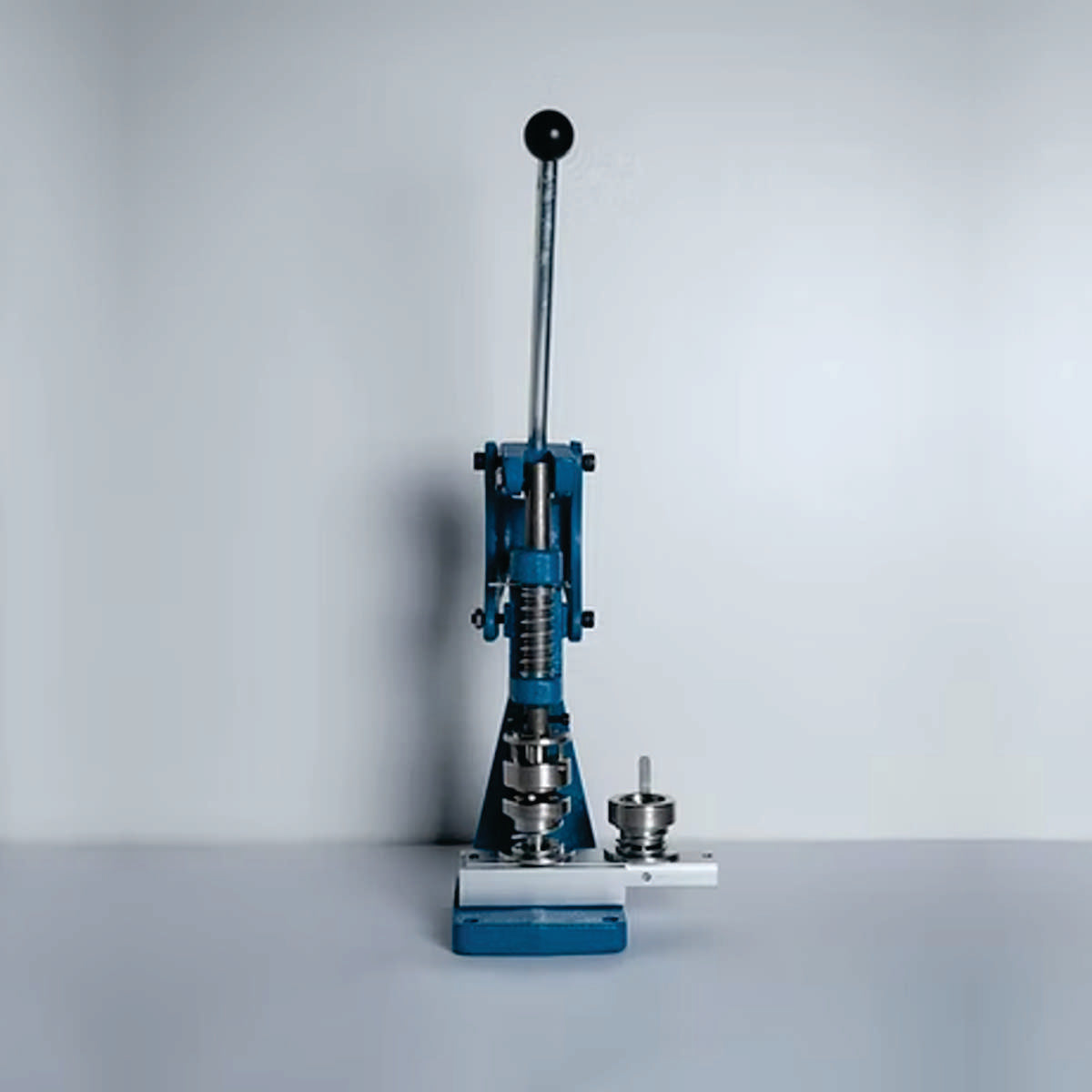 Prensa manual para presión controlada en trabajos de tapicería, específicamente para la colocación de botones forrados y otros elementos de fijación.ZM MHDD